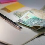 pieniądze, zeszyt i długopis leżące na stole