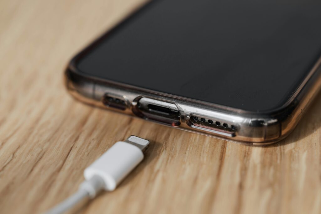 zbliżenie na smartfon i leżący obok kabel od ładowarki