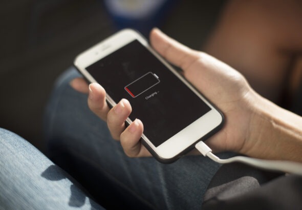 trzymany w ręku smartfon z ikoną ładowania baterii na ekranie