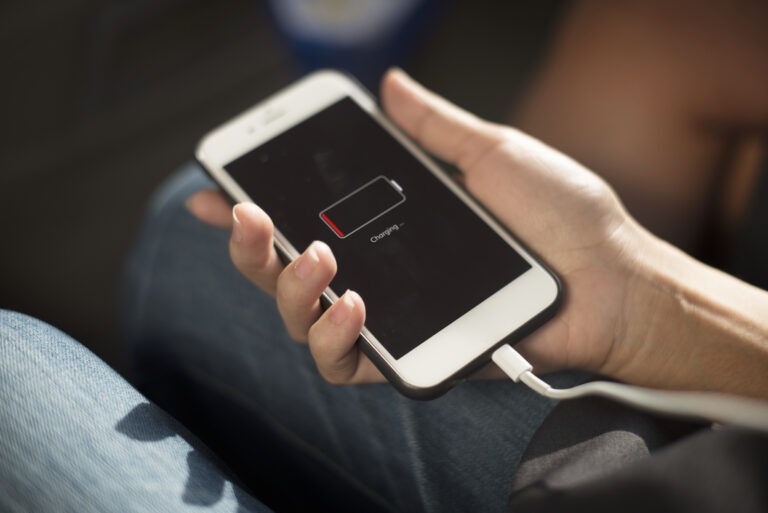 trzymany w ręku smartfon z ikoną ładowania baterii na ekranie